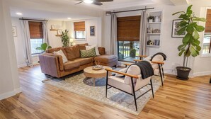 Una sala de estar moderna con sofá, sillón, mesa de centro y ventilador de techo.