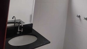 A bathroom with a sink, mirror, shower, and a window with a view. - Hotel Paraty (São Paulo)