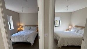 A bedroom with a bed, bedside table, lamp, and window. - Guest house overlooking Lough Conn (Foxford)