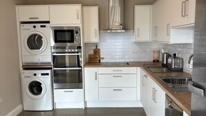 A modern kitchen with built-in appliances, white cabinetry, and a wooden countertop. - Guest house overlooking Lough Conn (Foxford)