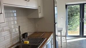 A modern kitchen with white cabinets, a stainless steel sink, and a built-in dishwasher. - Guest house overlooking Lough Conn (Foxford)