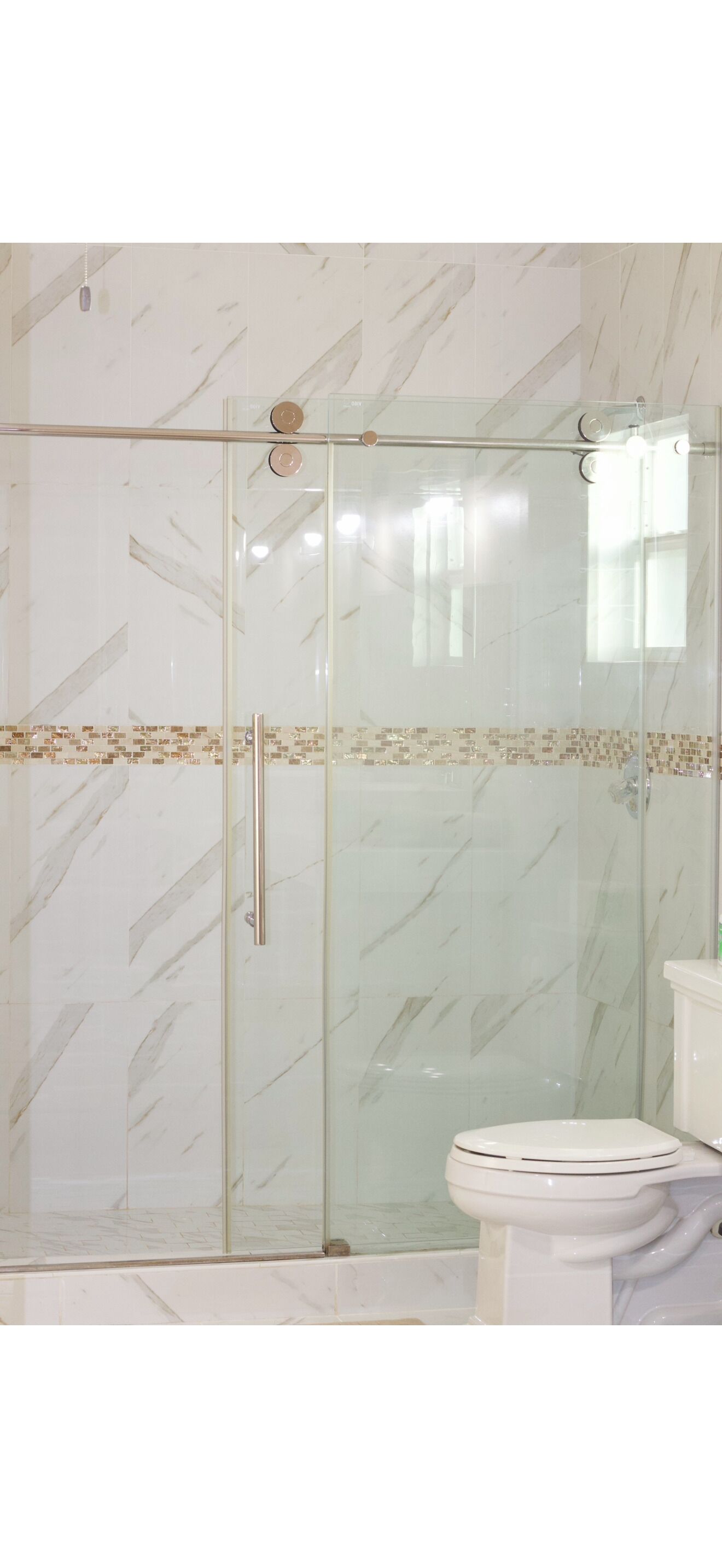 Un baño con cabina de ducha de vidrio, inodoro y pared con diseño de mármol.