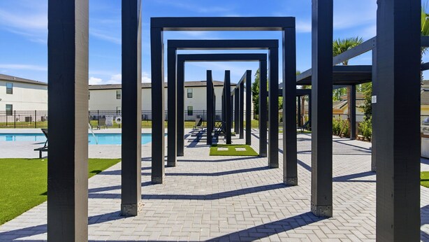En innergård med en geometrisk metallkonstruktion, en swimmingpool och en byggnad i bakgrunden.