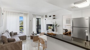 A modern kitchen with a central island, a dining area with a sofa, and a living room with a large window. - NEW Cozy Apt | Near Universal, Icon Park & IDrive (6165-1304) (Orlando)