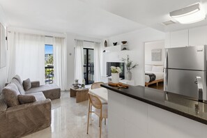Une cuisine moderne dotée d’un îlot central, un coin repas avec un canapé et un salon avec une grande fenêtre.