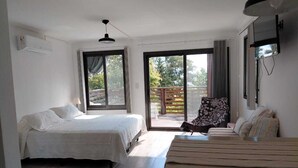 Une chambre avec un lit, un banc en bois, une chaise et un balcon avec vue.