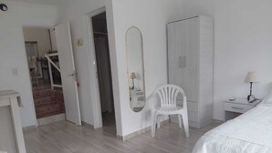 Une chambre à coucher avec un lit, une armoire, une chaise et un miroir.