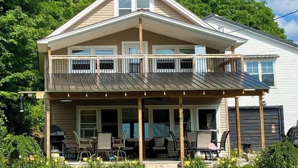 Ein zweistöckiges Haus mit überdachter Veranda, Garage und gepflegtem Rasen.
