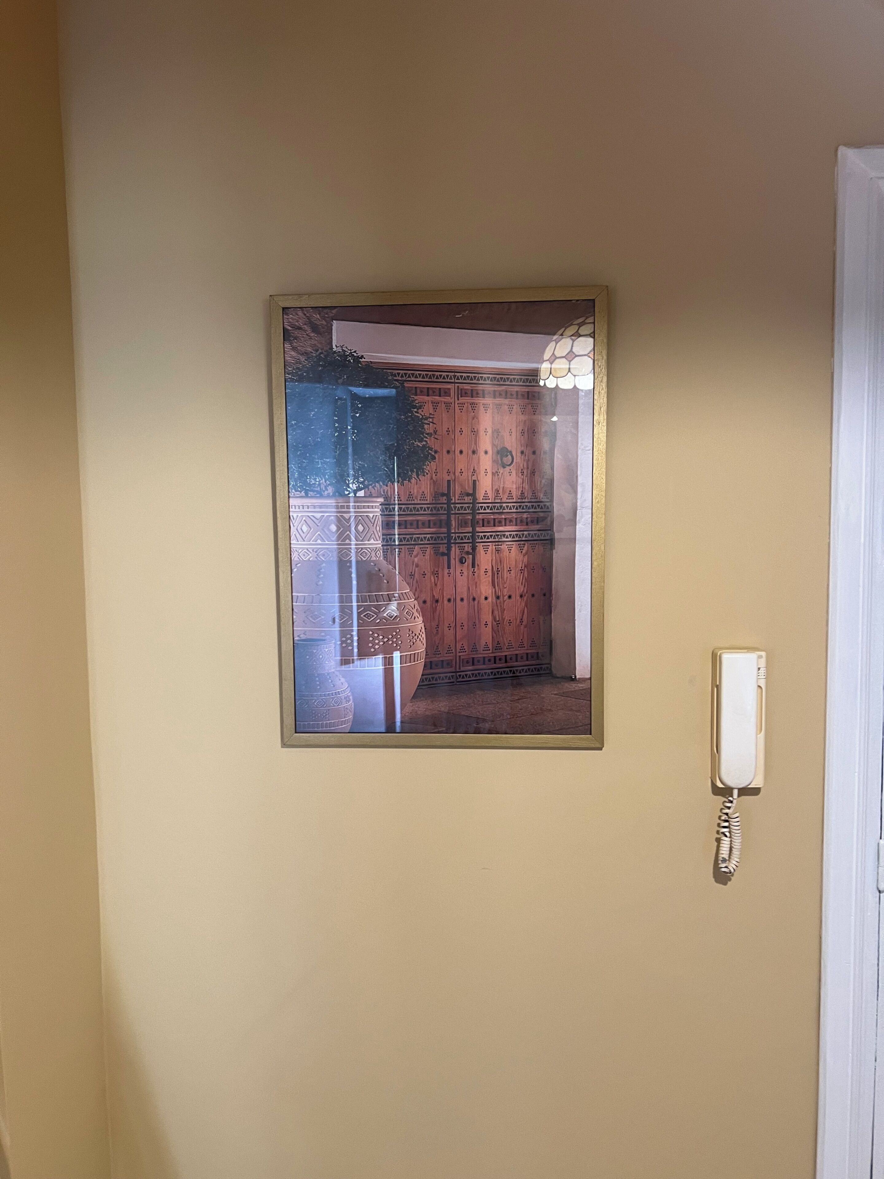 A framed picture of a room with a wooden door and a hanging light fixture.