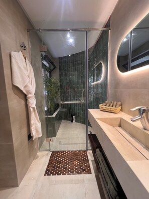 A modern bathroom with a glass shower enclosure, a towel rack, a sink with a basket, and a patterned mat. - Studio L 2 min from the corniche and ain diab (Casablanca)