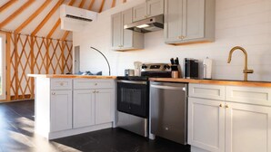 A modern kitchen with white cabinets, stainless steel appliances, and a wooden ceiling. - Goldfinch Yurt - Scenic Mountain Retreat (Rising Fawn)