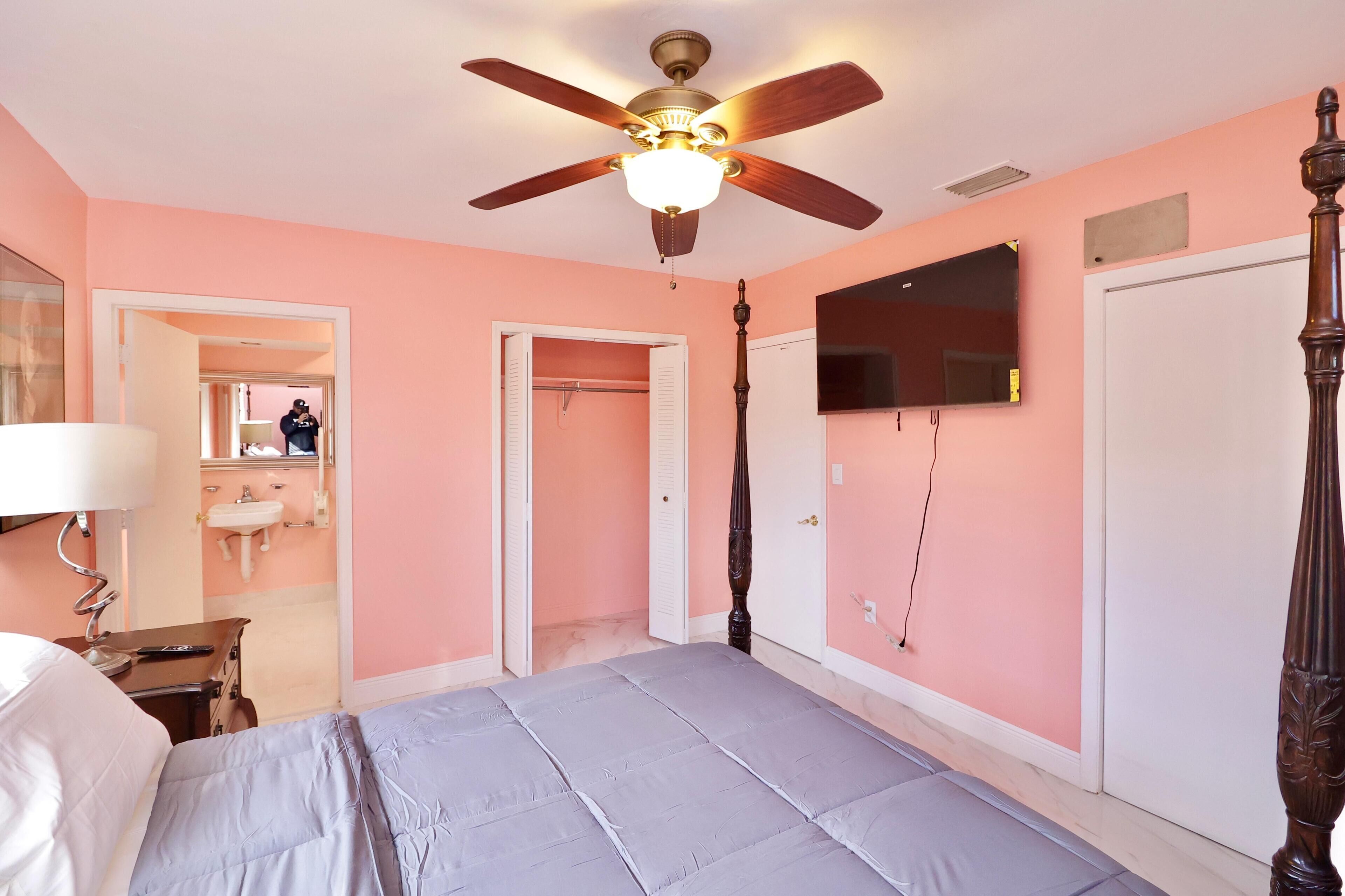Un dormitorio con cama, ventilador de techo, televisor y armario.