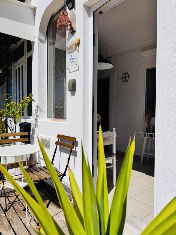 Eine Terrasse mit weißem Tisch und Stühlen, einer Holzbank und einer hängenden Leuchte.