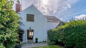 Ein eingeschossiges Haus mit geneigtem Dach, einer Haustür und einem kleinen Veranda-Bereich.