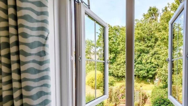 Ein Fenster mit Blick auf einen Garten und Bäume.