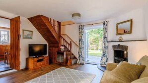 Ein geräumiges Wohnzimmer mit einer Holztreppe, einem Fernseher, einem Kamin und einem großen Fenster.