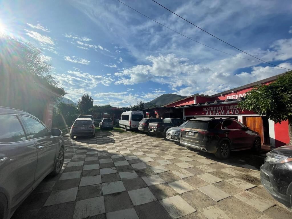 A parking area with cars, a checkered pavement, and a building with a sign that reads 'RESTAURANT TURISMO AEPAMAYO'.
