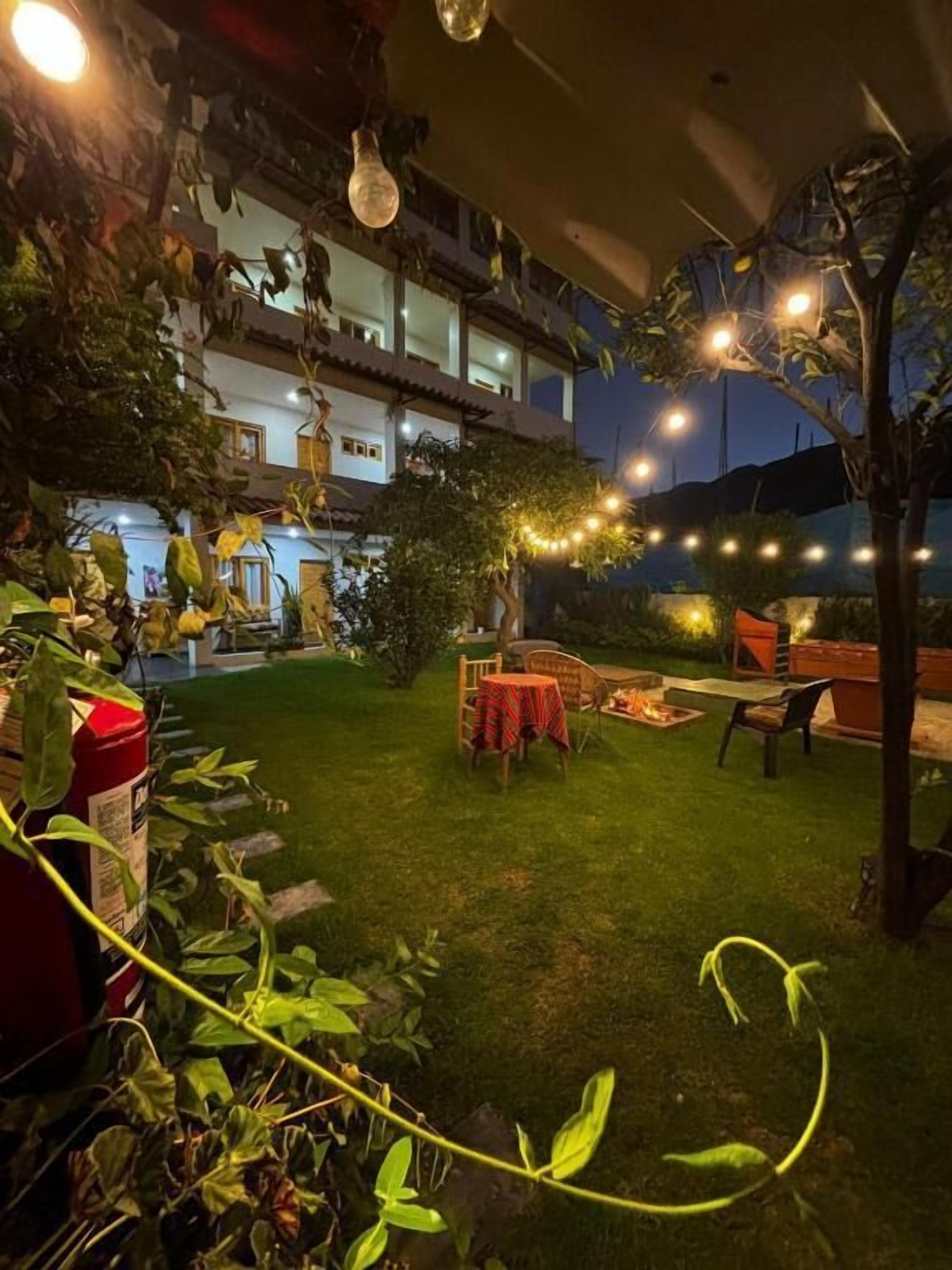 A courtyard with a dining area, string lights, and a fire pit.