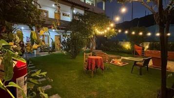Un cortile con zona pranzo, luci decorative a catena e un braciere.