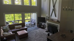 Amplia sala de estar con chimenea, televisor y un ventanal con vistas a una terraza.
