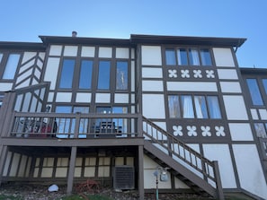 A two-story building with a balcony, a staircase, and a visible outdoor grill.