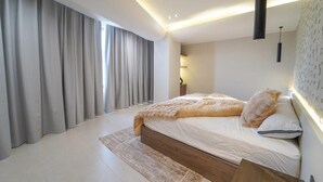 Een moderne slaapkamer met een groot bed, een nachtkastje, een lamp en een wandlamp.