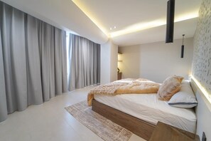 Ein modernes Schlafzimmer mit einem großen Bett, einem Nachttisch, einer Lampe und einer Wandleuchte.
