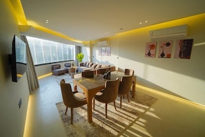 Ein modernes Wohnzimmer mit Essbereich, großen Fenstern und Kunstwerken an den Wänden.