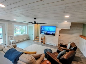 Un salon équipé d’un téléviseur, d’un ventilateur de plafond et d’un escalier menant à l’étage supérieur.
