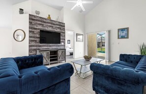 Ein modernes Wohnzimmer mit Kamin, Flachbildfernseher und blauen Sofas.