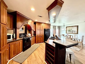 A kitchen with wooden cabinets, a stove, a microwave, and a refrigerator.