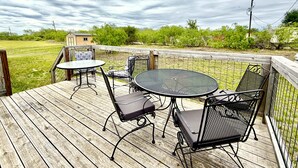 A wooden deck with outdoor furniture, a small table, and chairs.