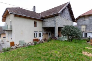 Ein zweistöckiges Gebäude mit geneigtem Dach, einem Balkon im oberen Stockwerk und einer kleinen Veranda.