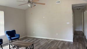 A room with a ceiling fan, a wooden floor, and a blue chair. - Tremendous 3-bedroom house with AC in friendly Cleveland. 275 (Cleveland)