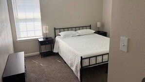 A bedroom with a bed, bedside tables, a window, and a carpeted floor. - Tremendous 3-bedroom house with AC in friendly Cleveland. 275 (Cleveland)