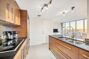 Une cuisine moderne avec un plan de travail noir, un évier en acier inoxydable et des armoires en bois.