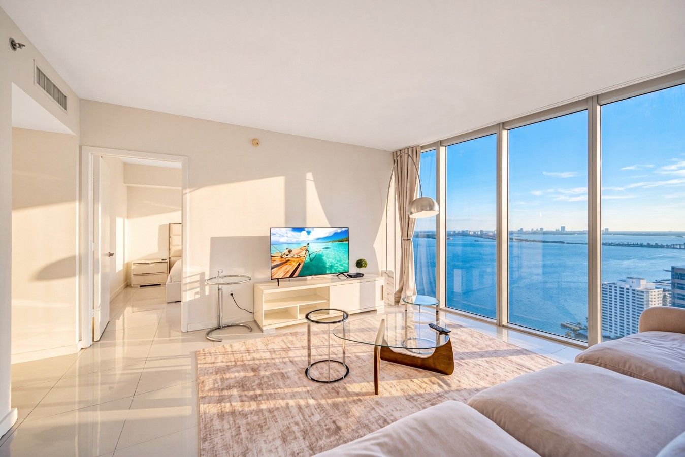 Una sala de estar moderna con un televisor grande, una mesa de centro de vidrio y un sofá.