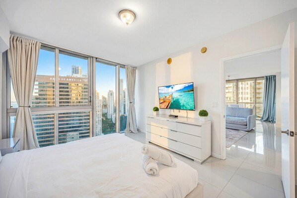 Een moderne hotelkamer met een groot bed, een flatscreen televisie, uitzicht over de stad en een balkon.