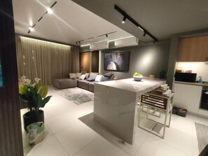 A modern kitchen with a central island, a dining area with a table and chairs, and a living room with a sofa and a coffee table.