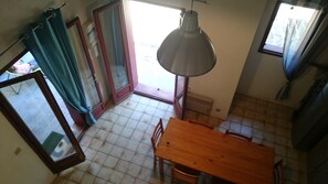 Una cucina con tavolo e sedie in legno, un lampadario a sospensione e una porta scorrevole in vetro che si apre su uno spazio all'aperto.