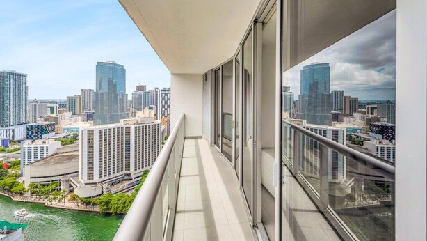 Un balcón con vista a la ciudad, ventanas amplias y cielo despejado.