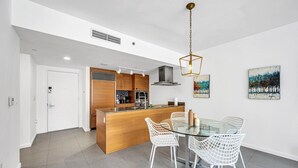 Una cocina moderna con una isla central, sillas blancas y una mesa de comedor de vidrio.