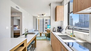 A modern kitchen with a dining area, a view of the city, and a small living space.