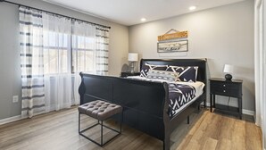 A bedroom with a bed, bench, nightstands, and a window with curtains. - 3BR/3BA at Pointe Royale - Golf, Pools & Dining (Branson)