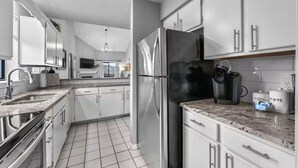 A modern kitchen with stainless steel appliances, white cabinetry, and a tiled floor. - 3BR/3BA at Pointe Royale - Golf, Pools & Dining (Branson)