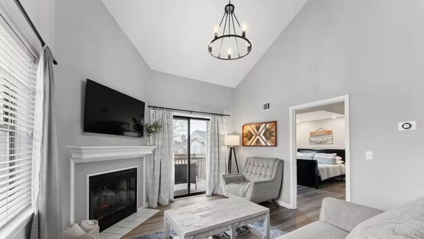 A modern living room with a fireplace, a television, and a chandelier. - 3BR/3BA at Pointe Royale - Golf, Pools & Dining (Branson)