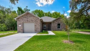 A single-story house with a stone facade, a garage, and a well-maintained lawn.