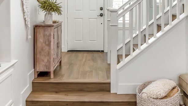 A staircase leading to a door, a wooden cabinet with a plant, a woven basket, and a patterned rug. - Serene 3-bedroom house with Tesla Charger in Ladera Ranch (Mission Viejo)