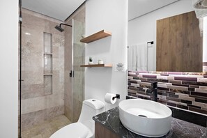 Ein modernes Badezimmer mit einer Duschkabine aus Glas, einer weißen Toilette, einem мраморным Waschbecken und einem hölzernen Regal.