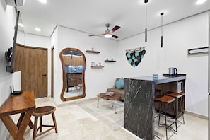 Eine moderne Küche mit einer Marmorinsel, Holzstühlen, einem Deckenventilator und einem Essbereich inklusive Sofa und Couchtisch.